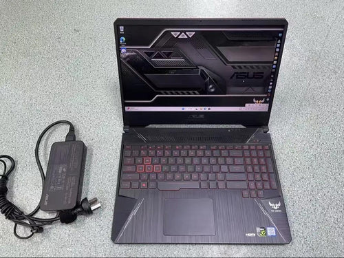 ASUS TUF Gaming 15-inch laptop with red accents and power adapter